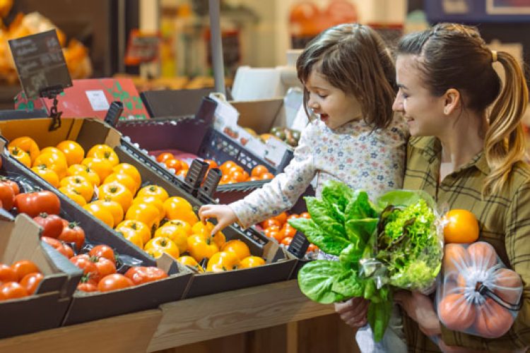 Mother and young daughter choosing produce